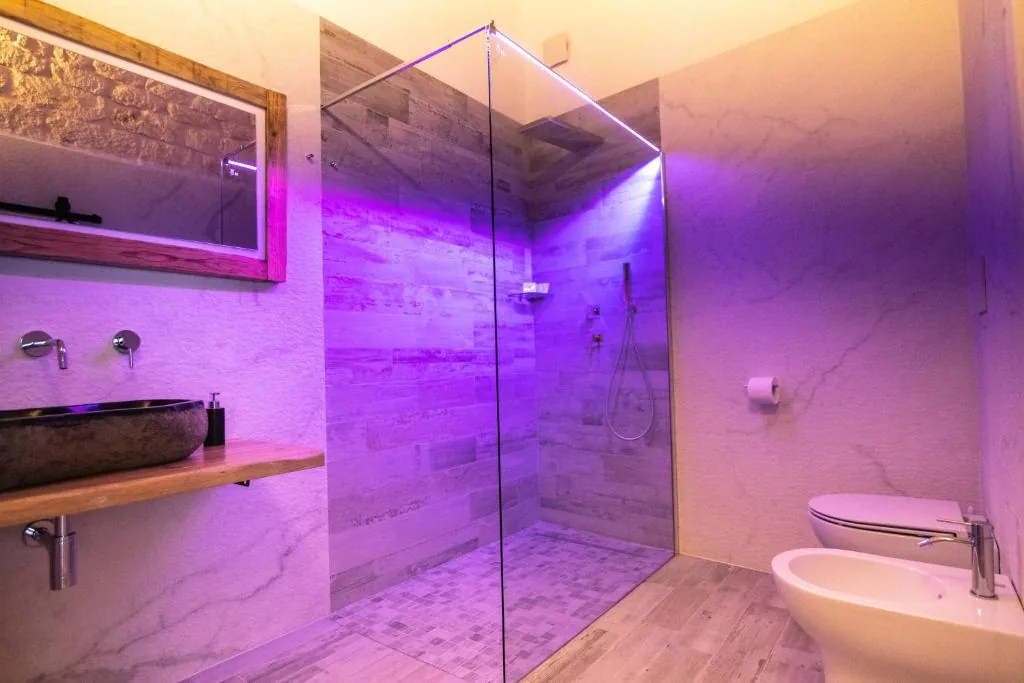 Walk-in glass shower bathed in violet light
